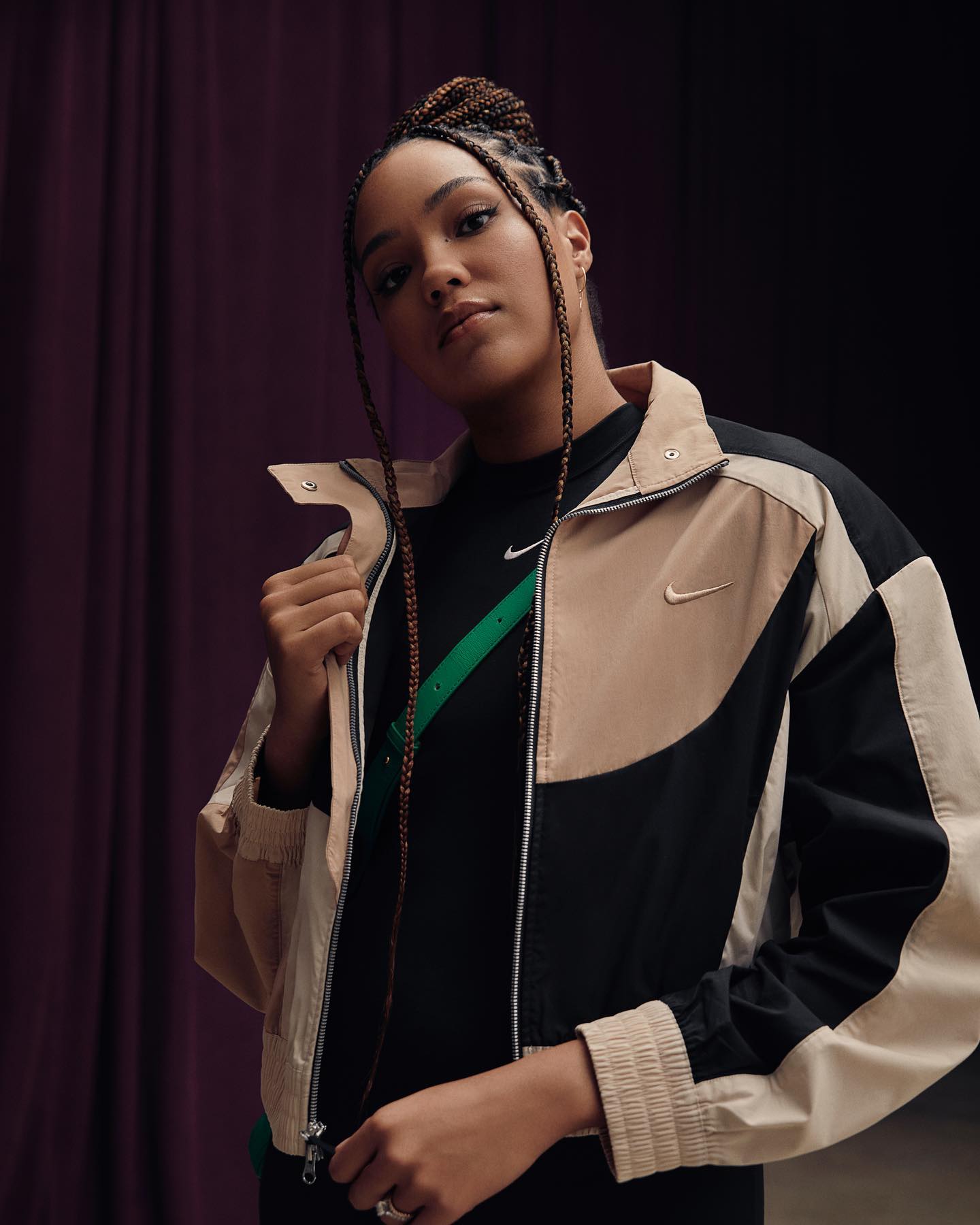 An athlete in a color-blocked Nike windbreaker against a dark pleated curtain