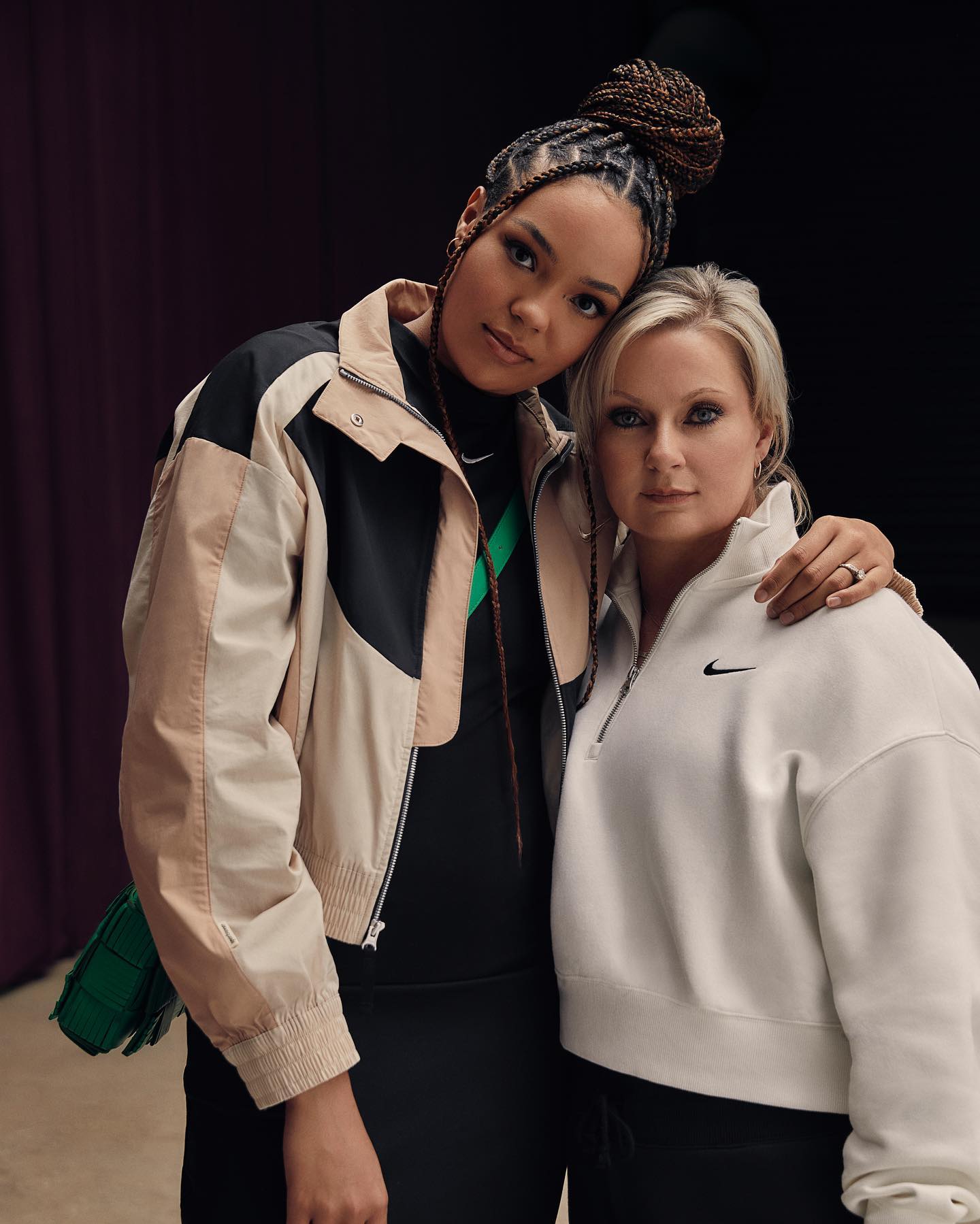 An athlete and her mother in Nike apparel, arms around each other, against a dark curtain
