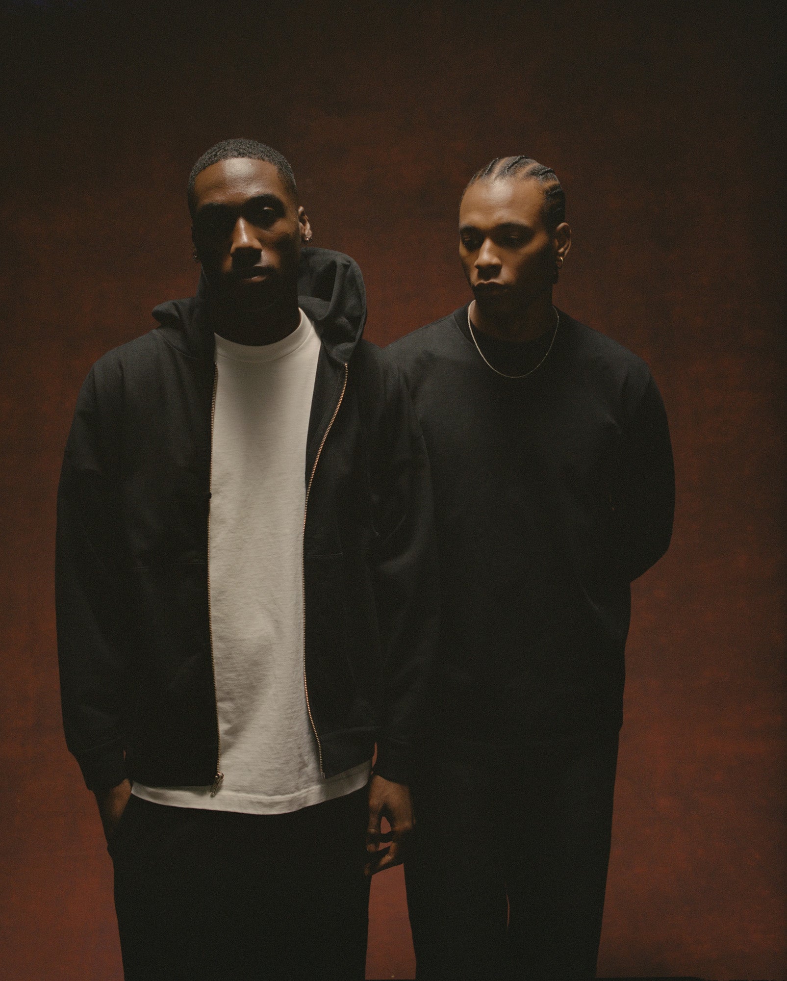 Two models wearing Young Vets clothing against a warm studio backdrop